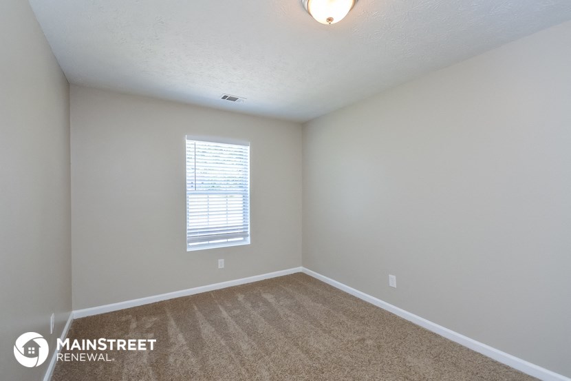 the spacious living room with carpeted flooring and window