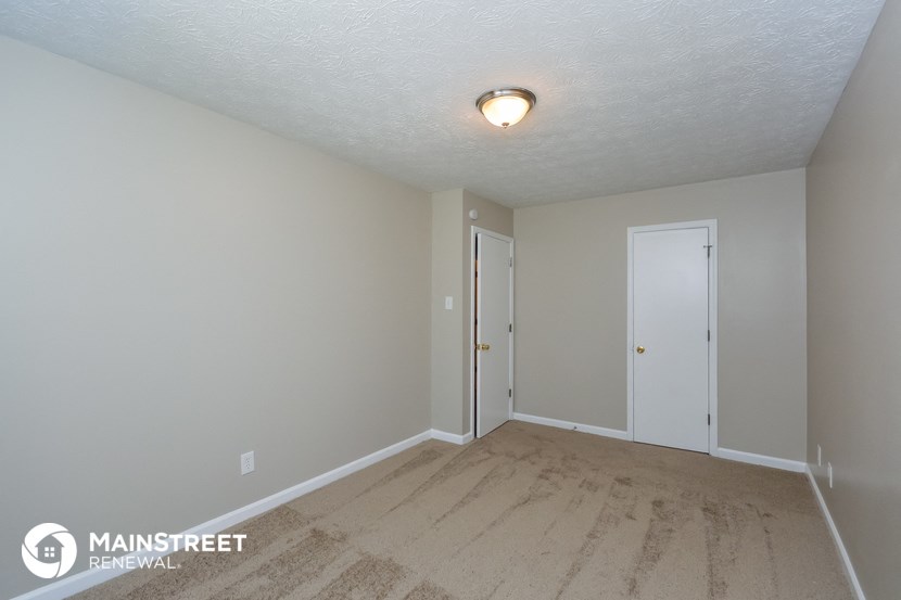 the spacious living room with wood flooring and white walls