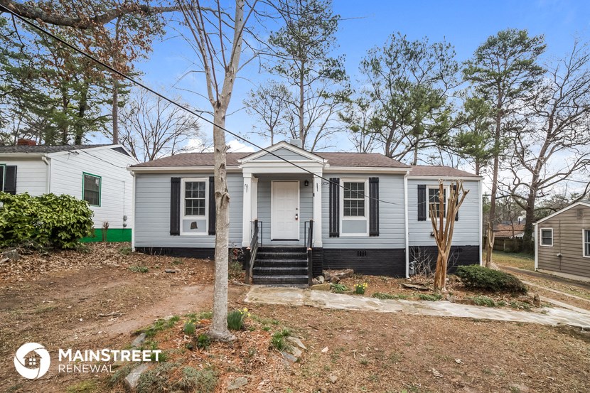 a small white house with a front porch and some trees