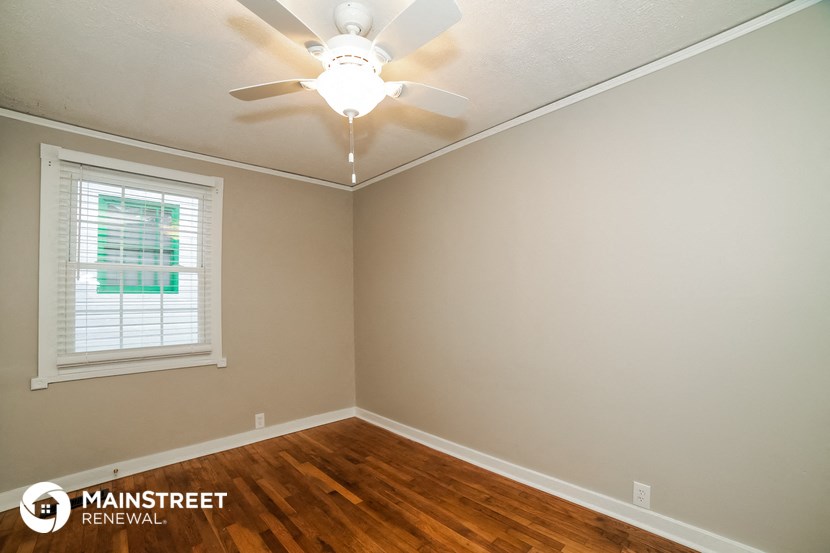 the bedroom with wood floors and a ceiling fan