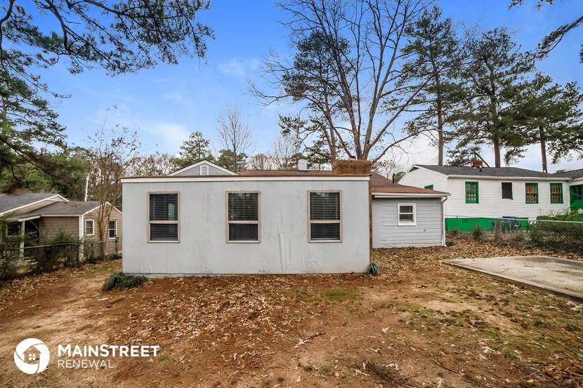 a small white house with a yard with dirt and trees