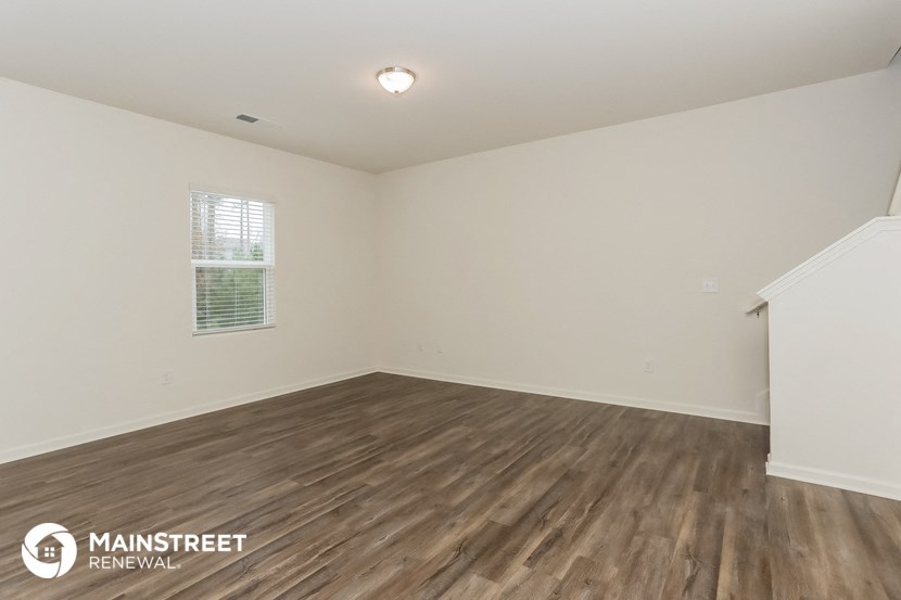 the spacious living room with wood flooring and white walls