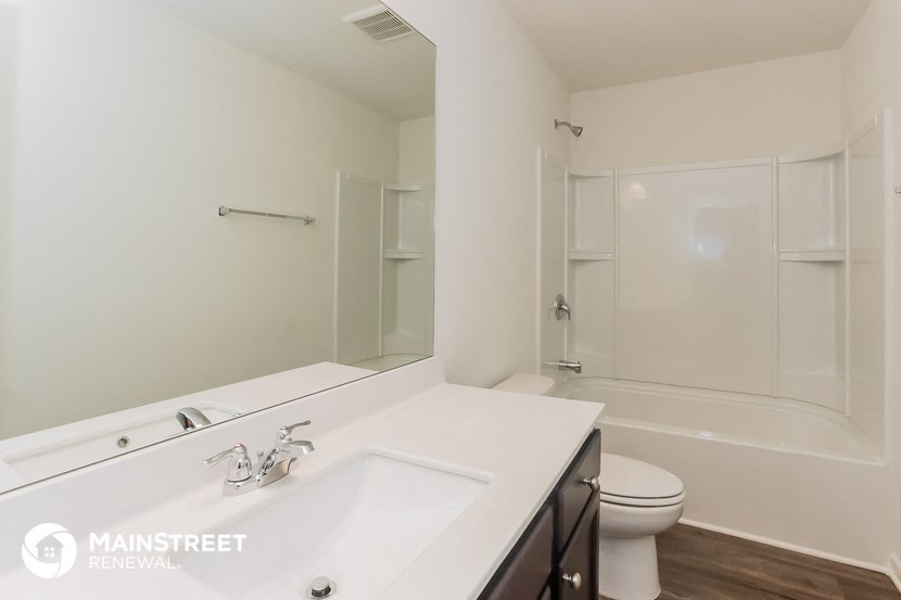 a white bathroom with a large mirror and a white toilet and sink