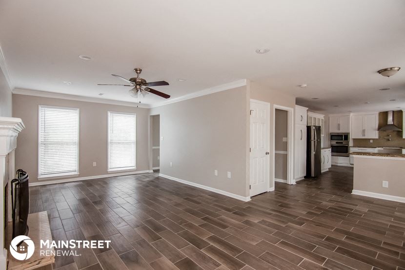 the living room and kitchen of an empty house with a ceiling fan