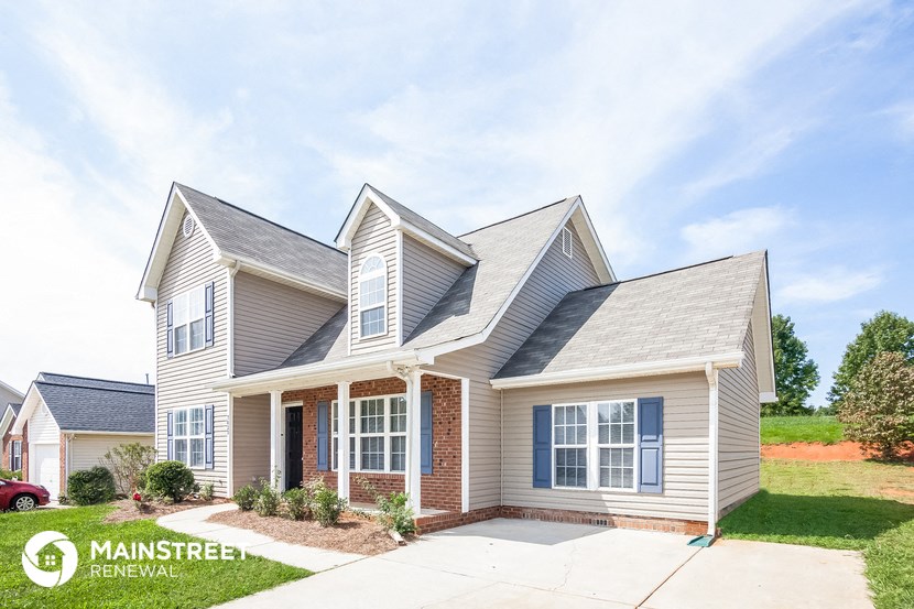a small house with a driveway and a lawn