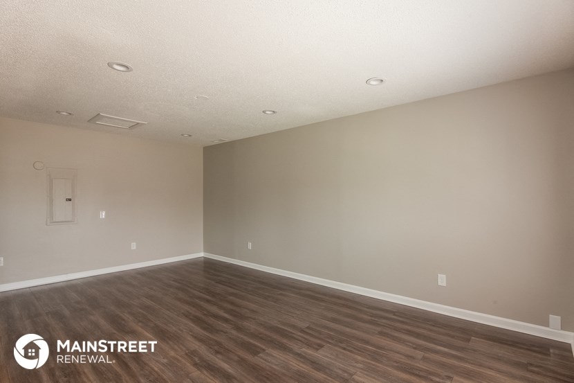 the spacious living room with wood flooring and white walls