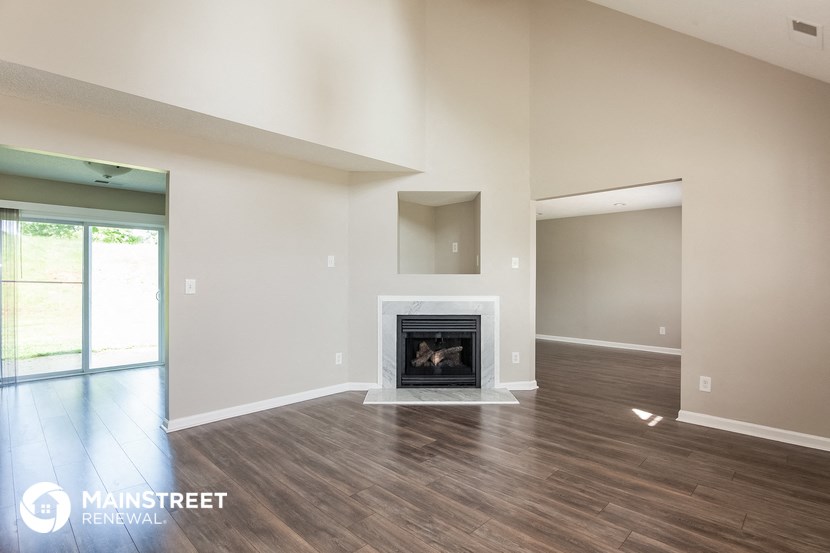 the living room with the fireplace and wood flooring