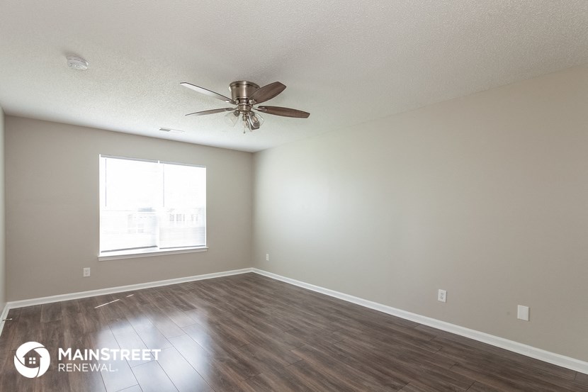 the spacious living room with ceiling fan and wood flooring
