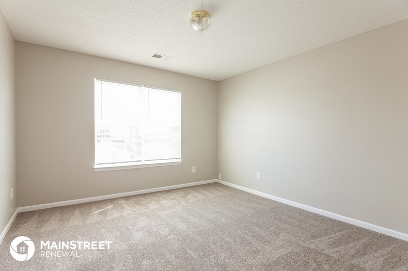 the spacious living room with carpeting and a large window