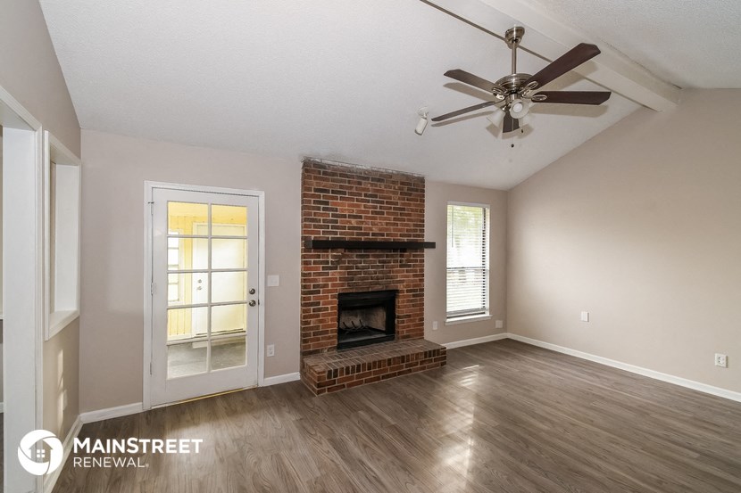 the living room of a home with a brick fireplace and a ceiling fan