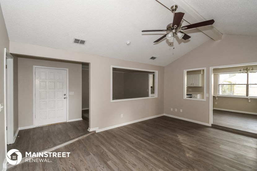a living room with a ceiling fan and a tv