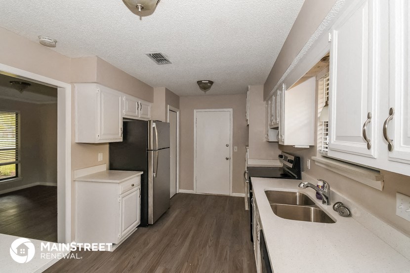 a kitchen with white cabinets and a sink and a refrigerator