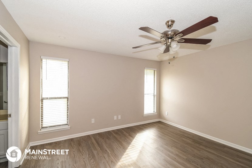 the spacious living room with ceiling fan and wood flooring