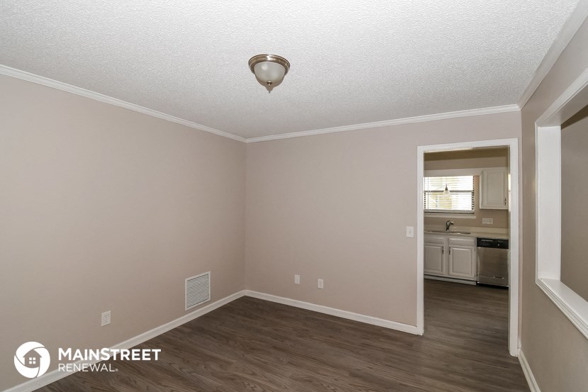 the spacious living room with hardwood flooring and an open doorway to the kitchen