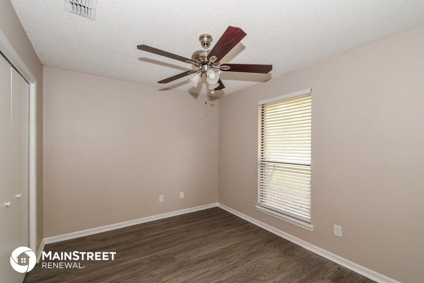 the interior of a bedroom with a ceiling fan and a window
