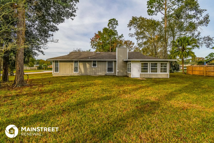 a small house with a grassy yard and trees