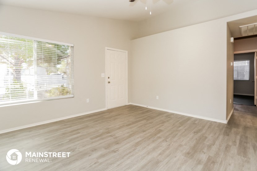 the living room of an apartment with wood flooring and a large window