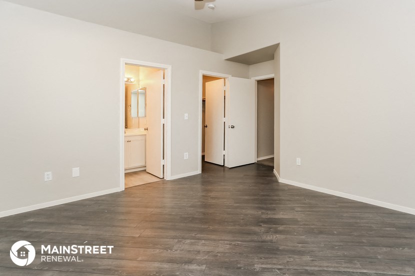 the living room of an apartment with wood flooring and white walls