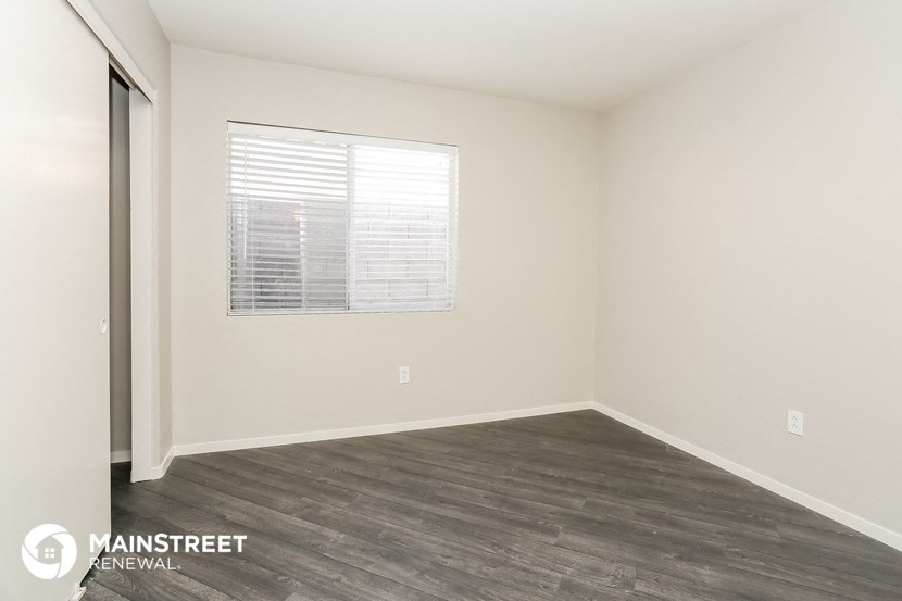 the spacious living room with wood flooring and a window