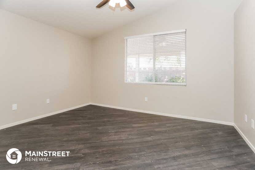 the spacious living room with wood flooring and a window