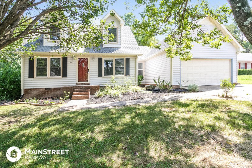 a white house with a front yard and a tree