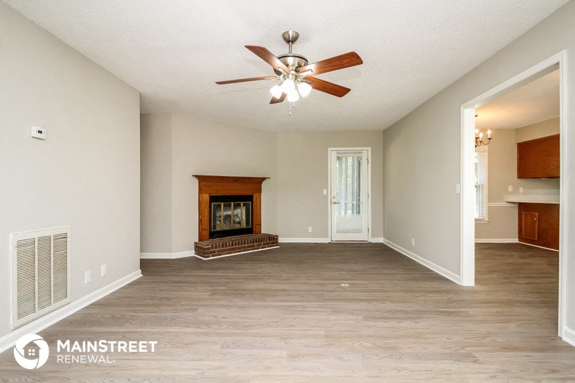 a living room with a fireplace and a ceiling fan