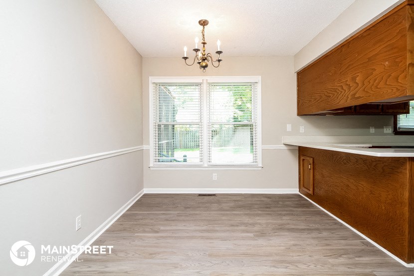 an empty kitchen with a large window and wooden cabinets