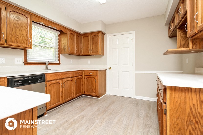 a kitchen with wooden cabinets and a white counter top and a door