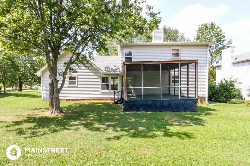 a small white house with a screened in porch and a tree
