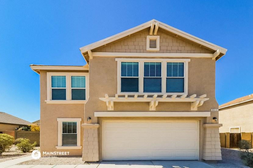 a tan house with a white garage door in front of it