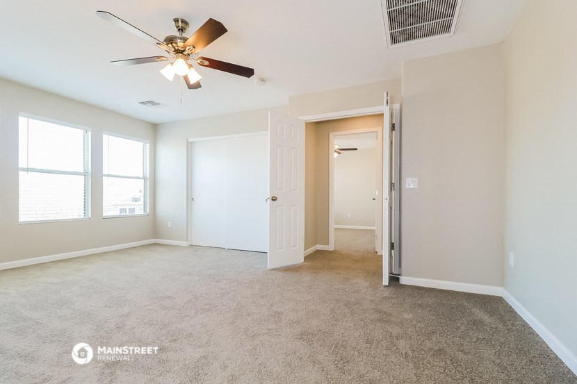 an empty living room with a ceiling fan and a closet
