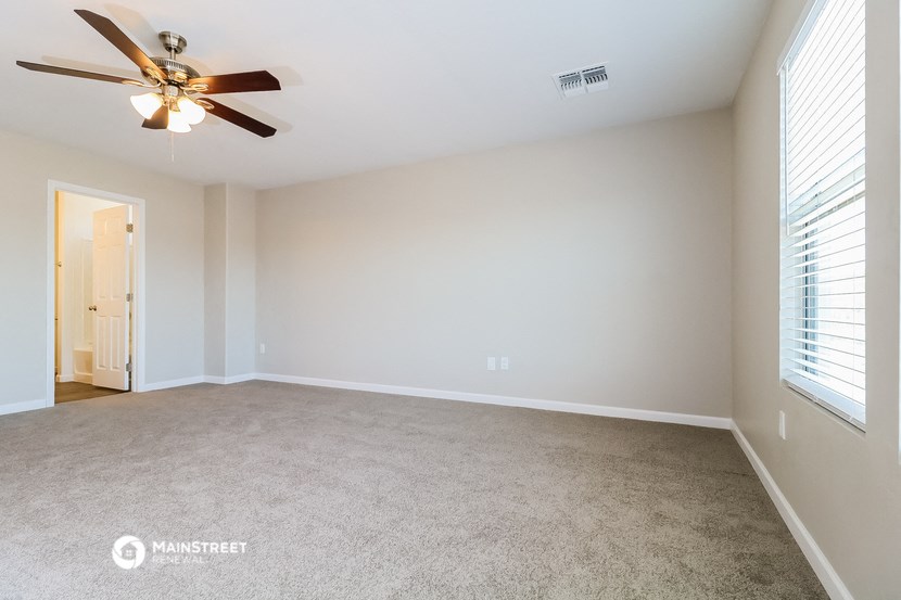 an empty living room with a ceiling fan and a window