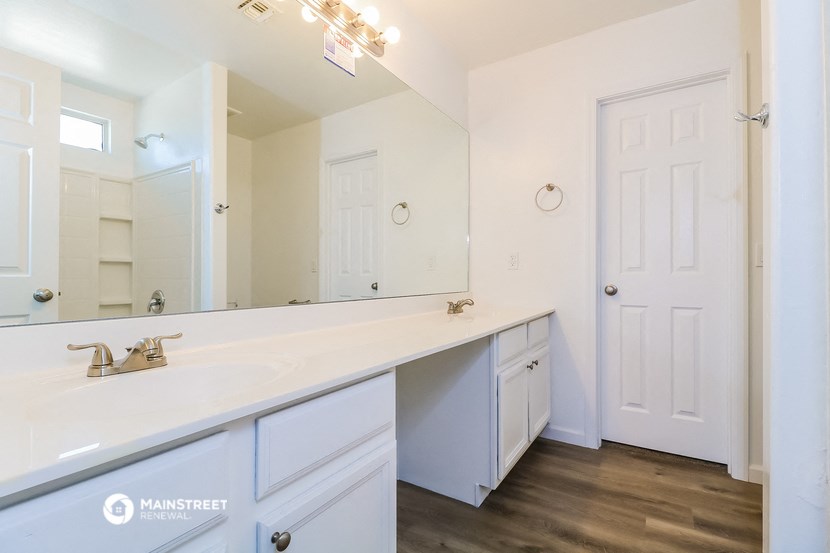 a white bathroom with a large mirror and a large sink