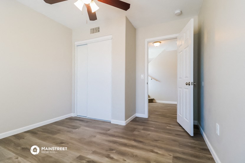 a bedroom with a ceiling fan and a door to a hallway