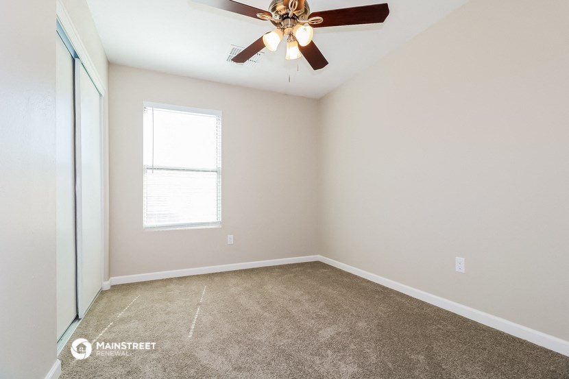 an empty room with a ceiling fan and a window