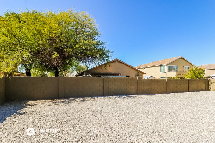 a retaining wall with a house behind it and a gravel driveway