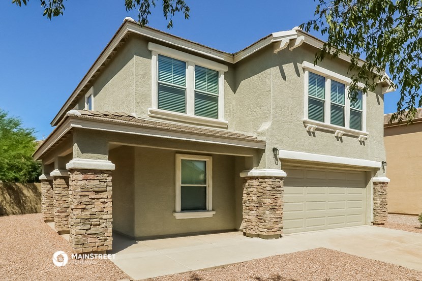 a tan house with green shutters and a sidewalk in front of it