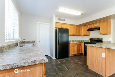 a kitchen with wood cabinets and black appliances and marble counter tops