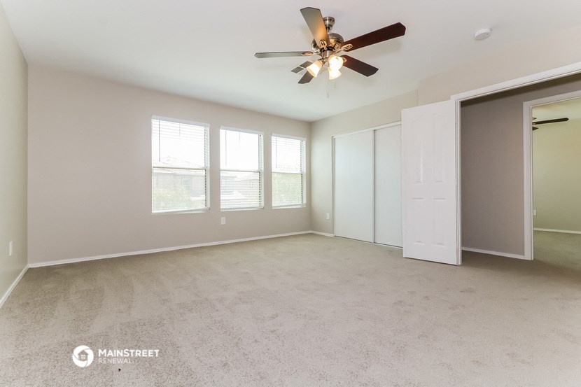 an empty living room with a ceiling fan and a closet