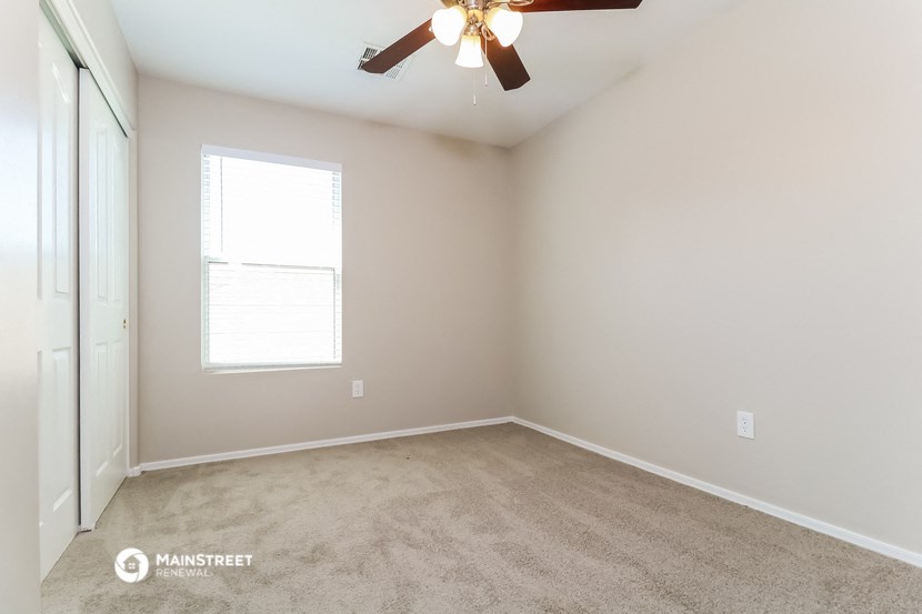 an empty room with a ceiling fan and a window