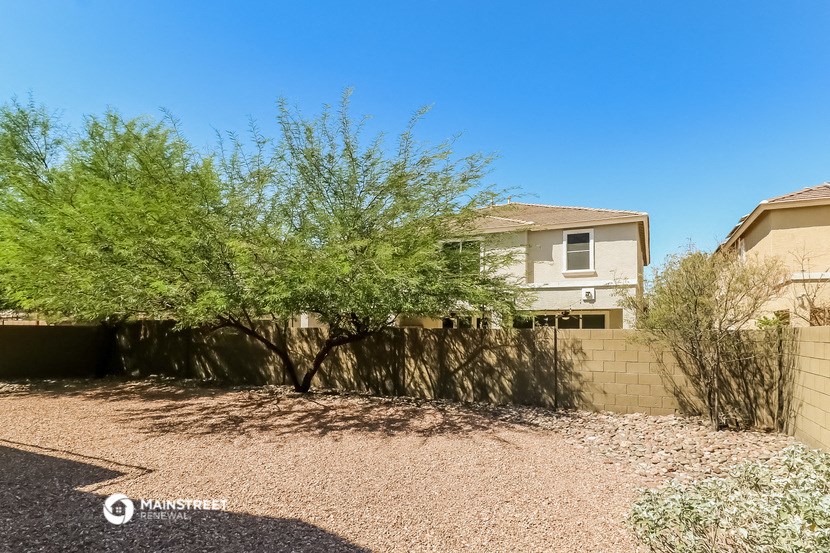 a home with a fence and a tree in front of it
