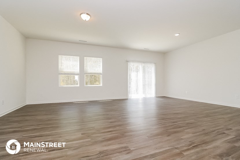 the spacious living room with wood floors and white walls