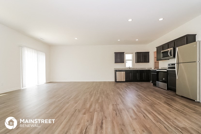 the living room and kitchen of an apartment with wood flooring