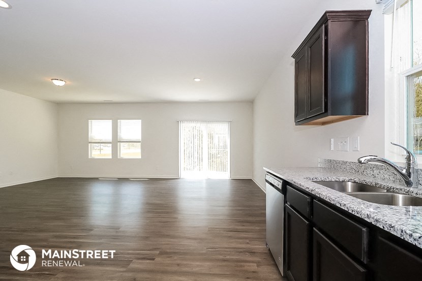 the kitchen and living room of a renovated home with a large window and a sink