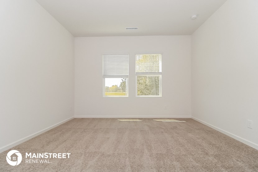 the spacious living room with carpeting and two windows