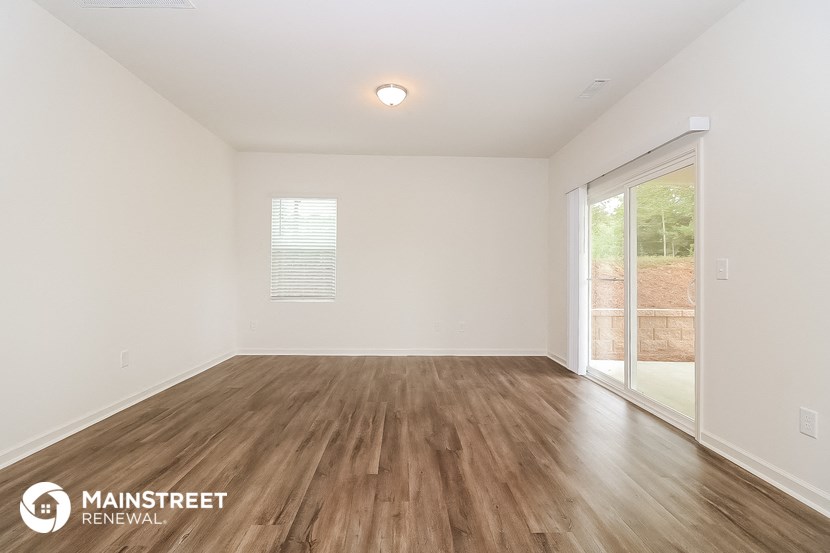 the spacious living room with wood flooring and a sliding glass door