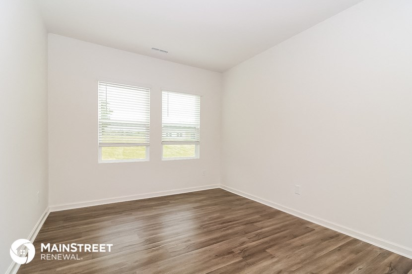 the spacious living room with wood flooring and two windows