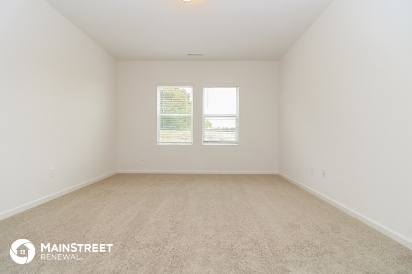 a room with carpet and two windows