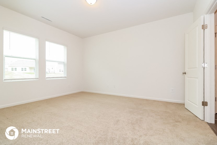 a bedroom with a carpeted floor and three windows