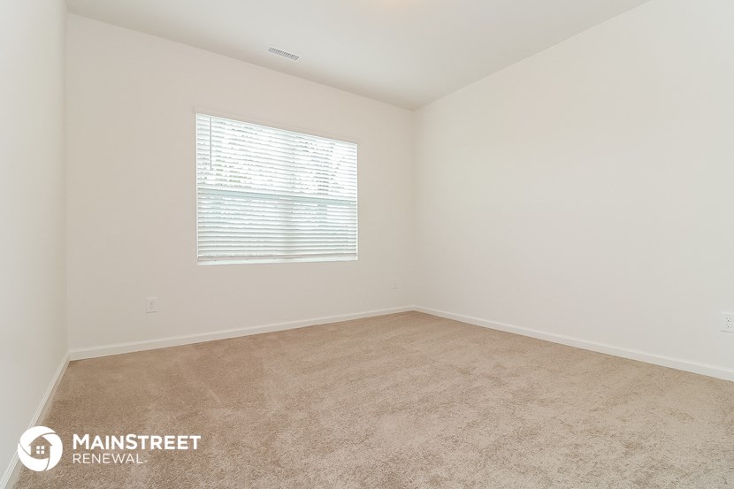 the spacious living room with carpeting and a window